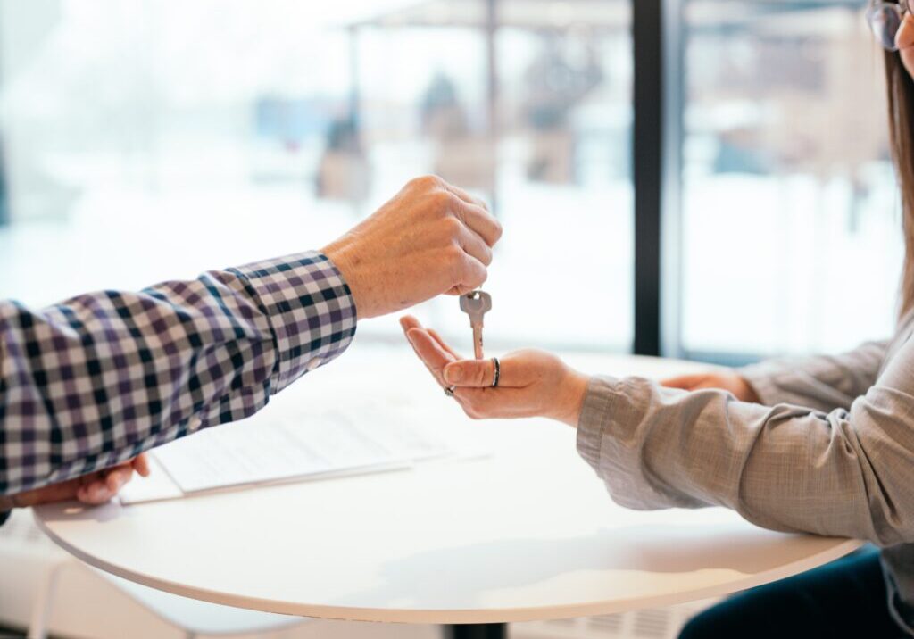 hand handing a person a house key
